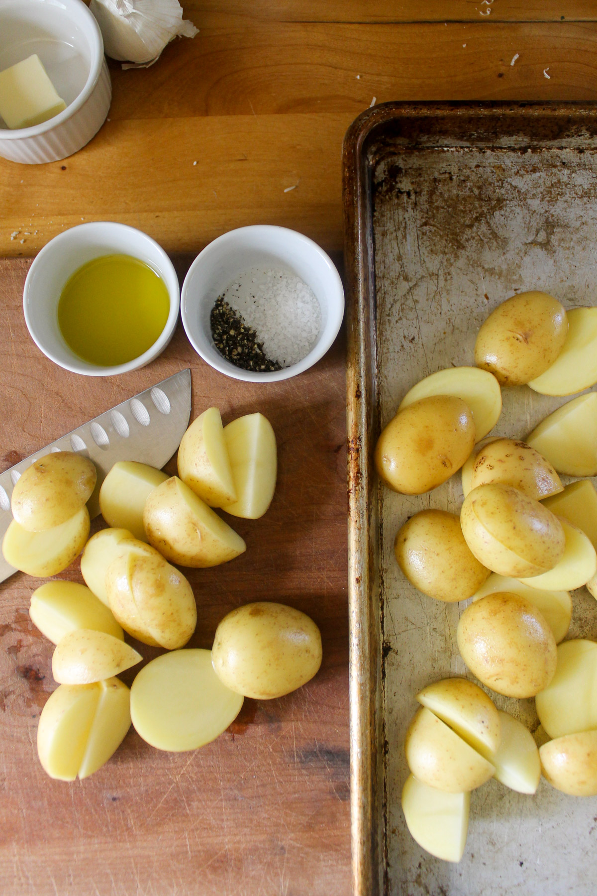 Cutting up potatoes on a cutting board and putting on a sheet pan.
