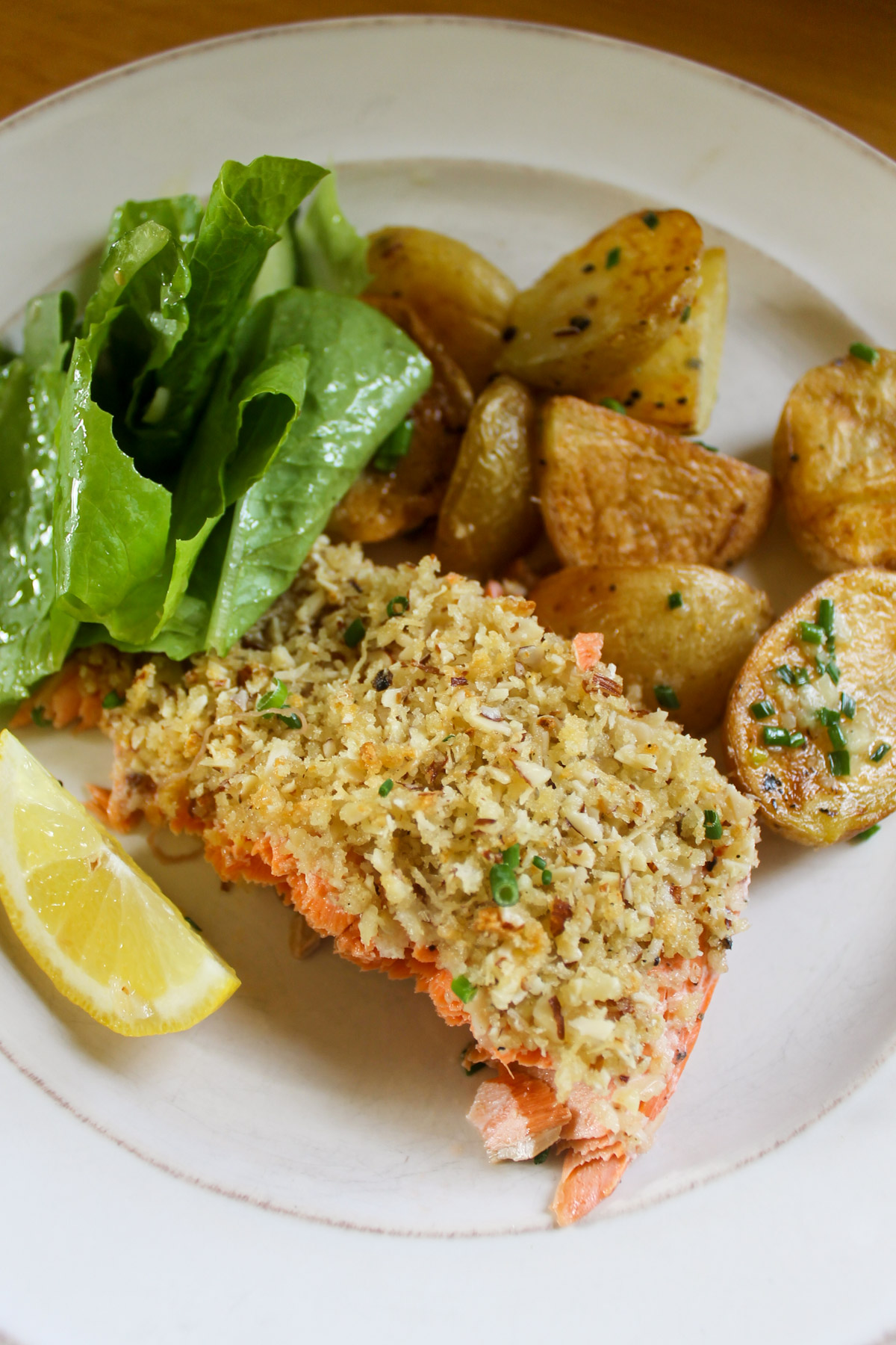A plate of almond salmon with potatoes and salad.