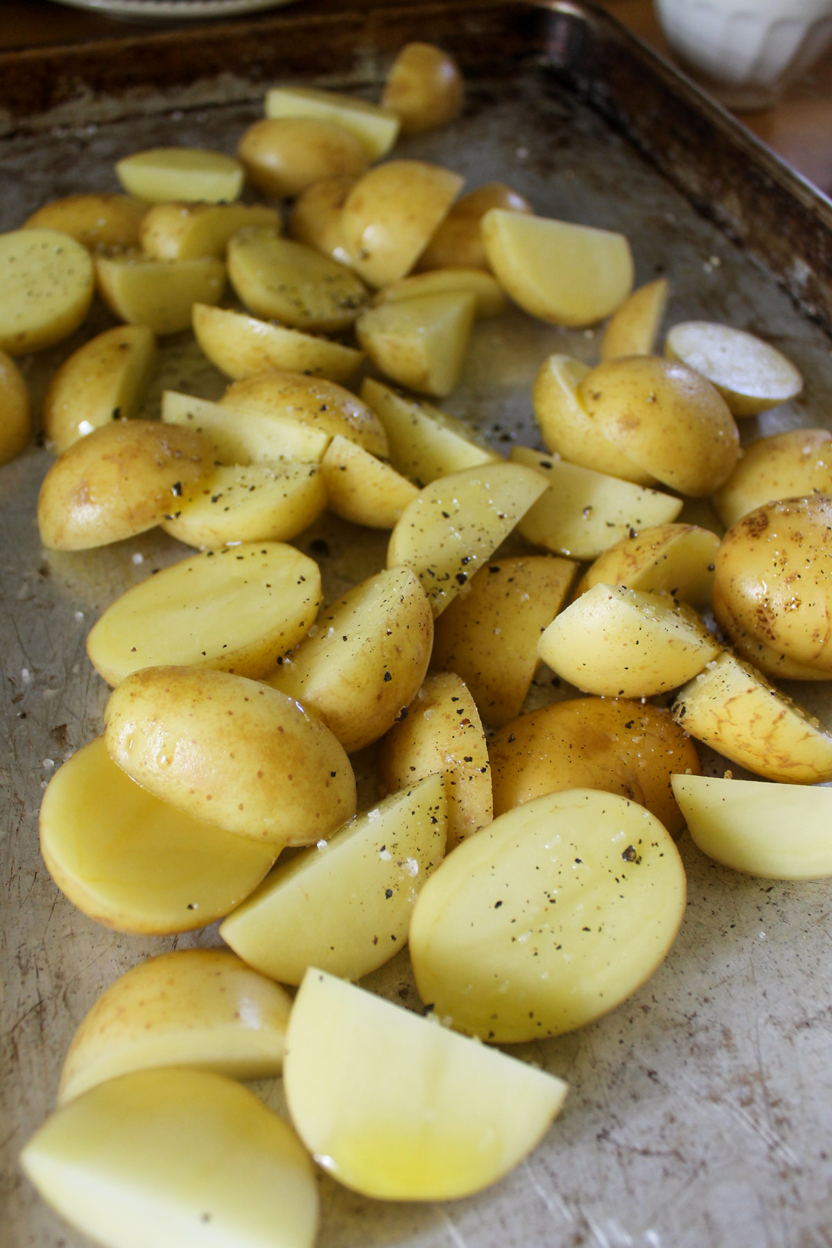 Potatoes seasoned on a sheet pan ready to bake.