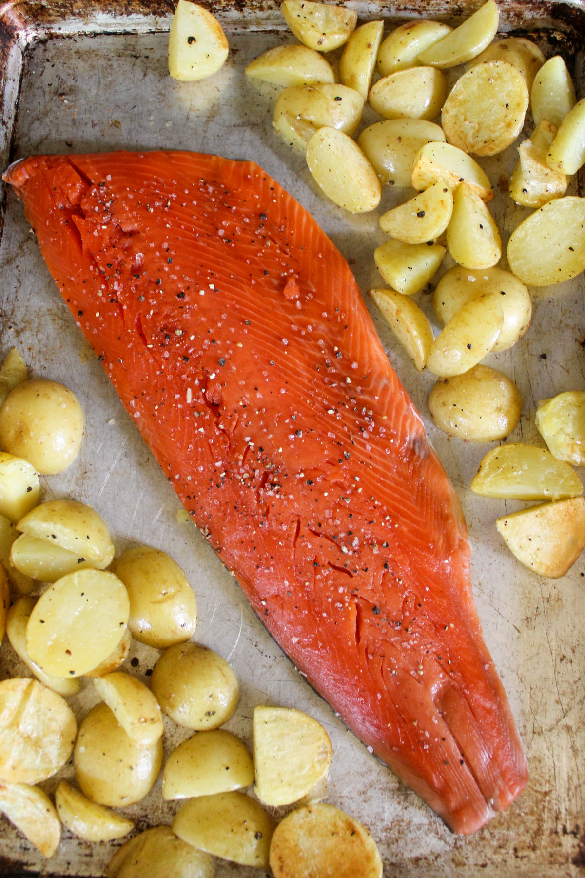 Par roasted potatoes on a sheet pan with the raw salmon filet.