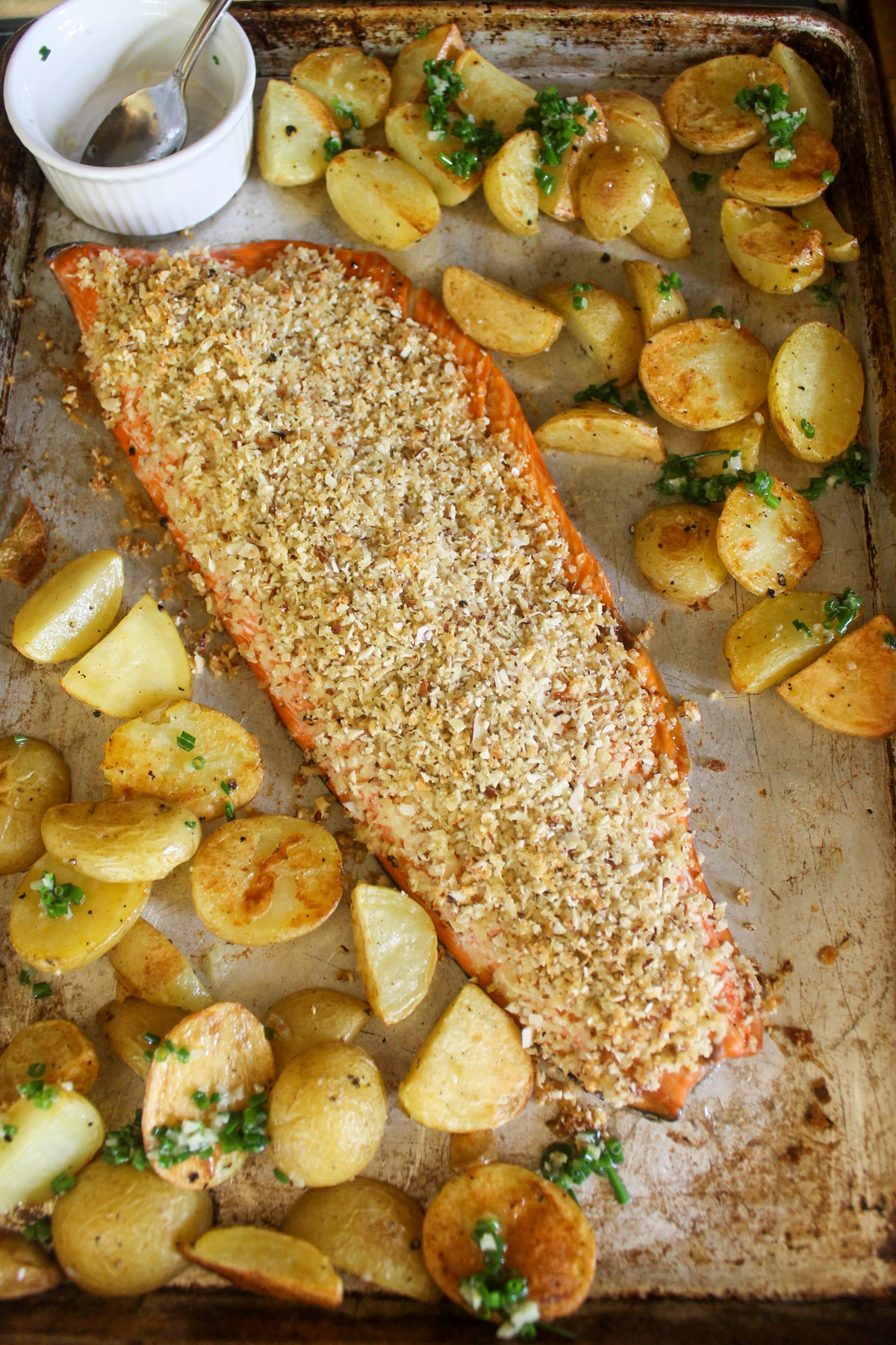 Baked almond crusted salmon filet on a sheet pan with crispy potatoes.