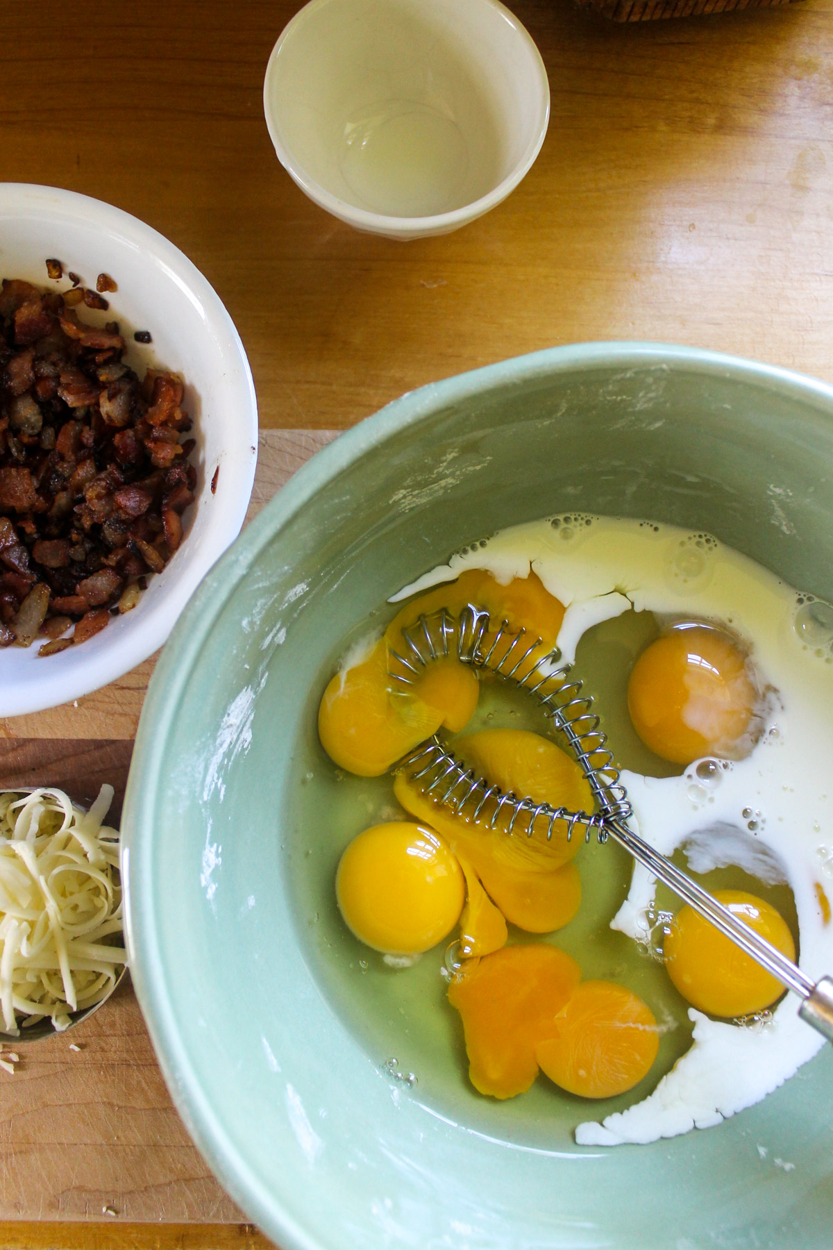A bowl of eggs with a whisk.