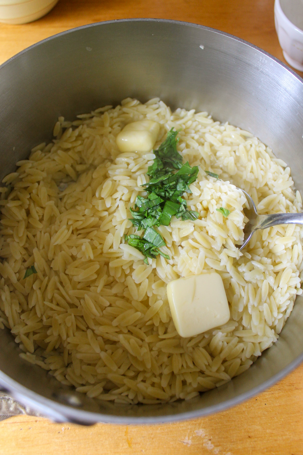 A pot of lemon orzo pasta with butter and herbs.