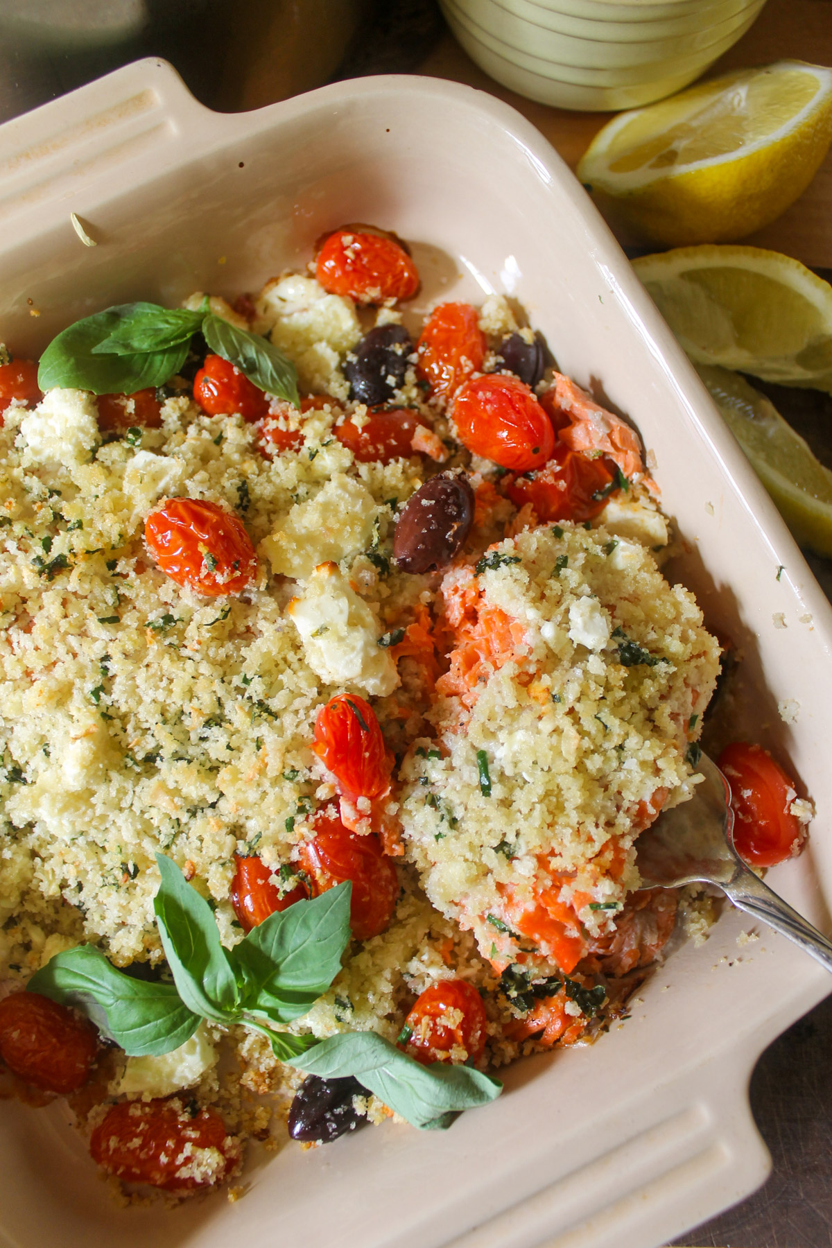 A baking dish with baked salmon, cherry tomatoes, and feta cheese.