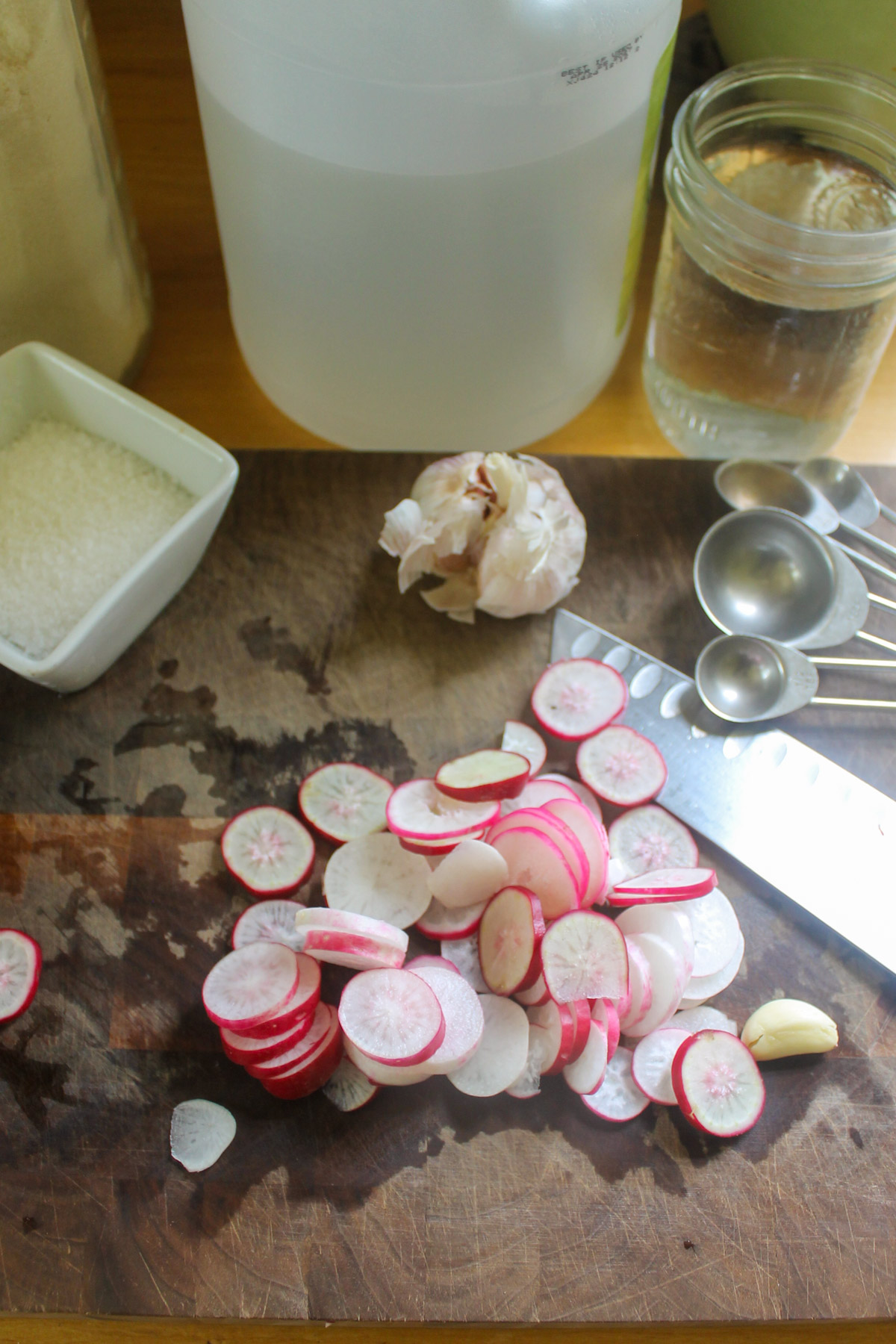 Sliced radishes on a cutting board with garlic.