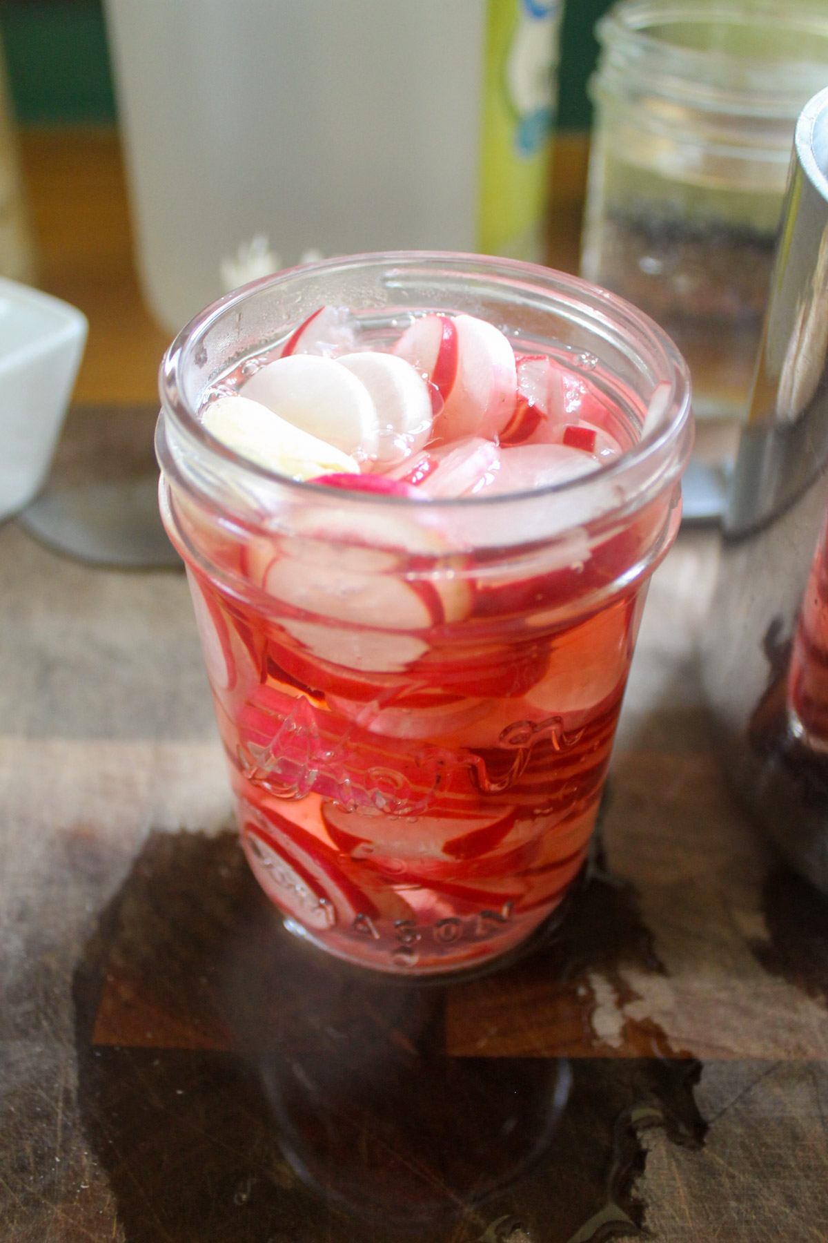 A jar of sliced radishes filled with brine.