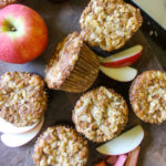 Apple Rhubarb muffins on a cutting board with apples.