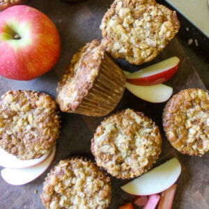 Apple Rhubarb muffins on a cutting board with apples.