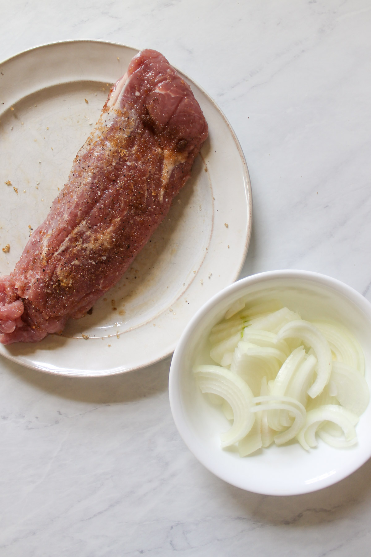 Seasoned pork tenderloin with sliced onions.
