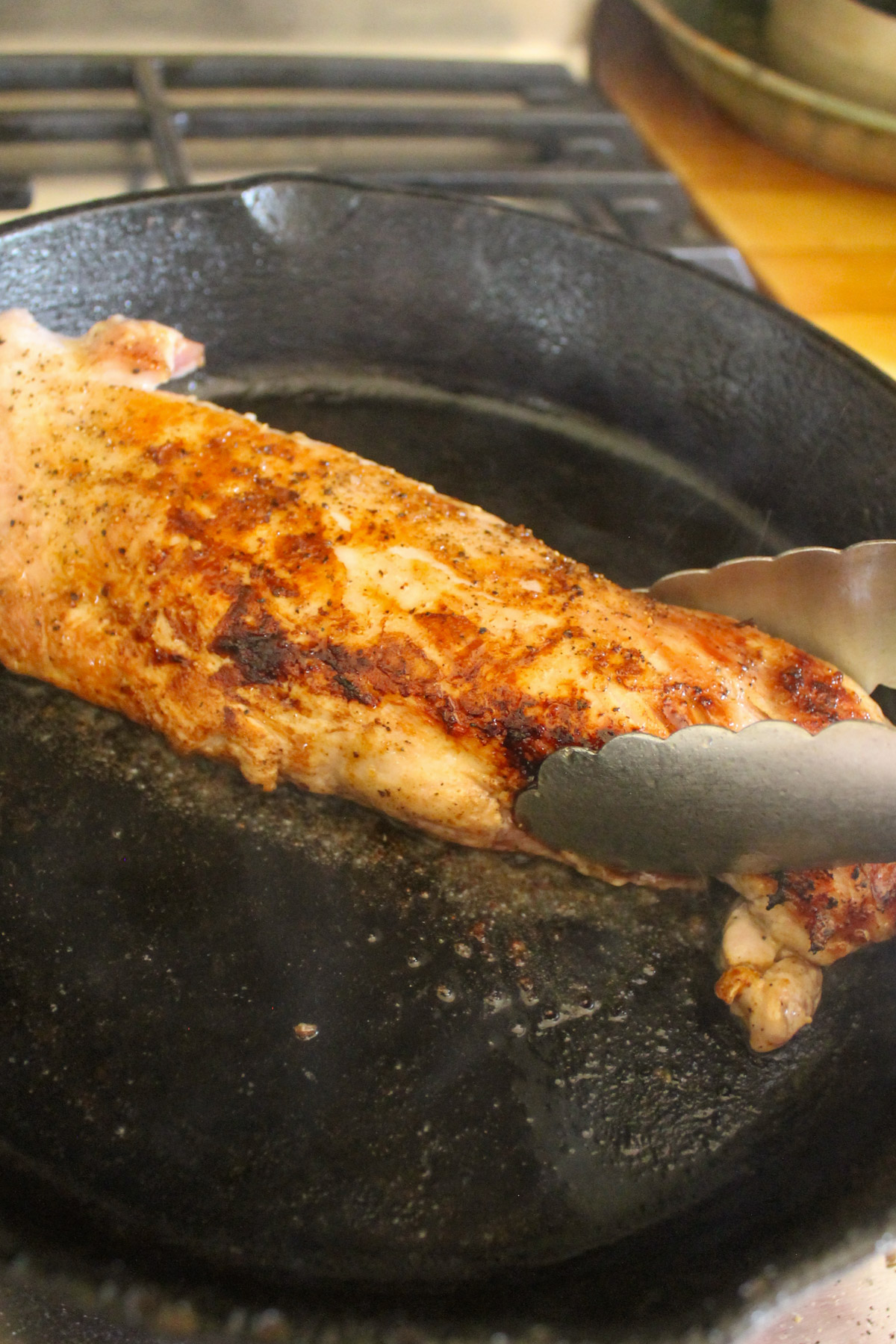 Searing a pork tenderloin in a cast iron skillet.