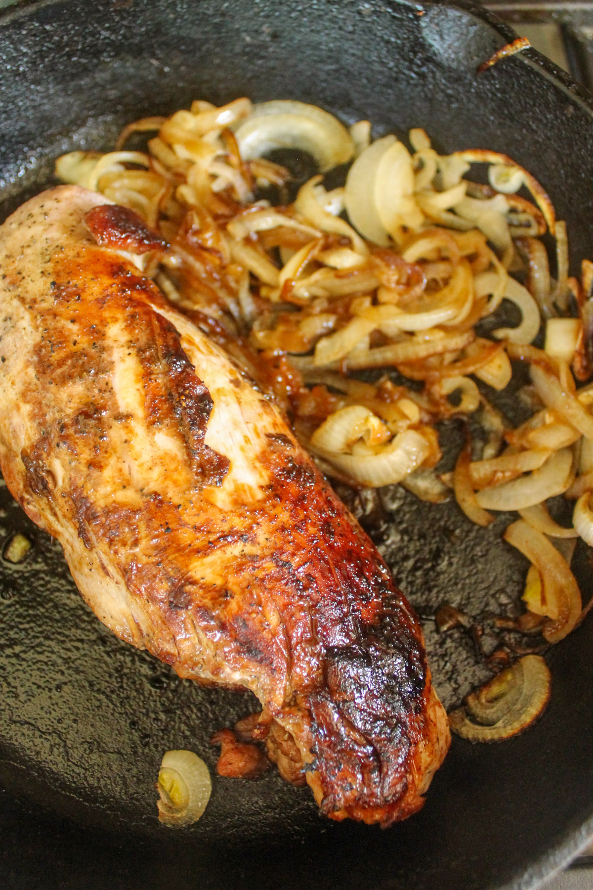 Oven roasted pork tenderloin with caramelized onions in a cast iron skillet.