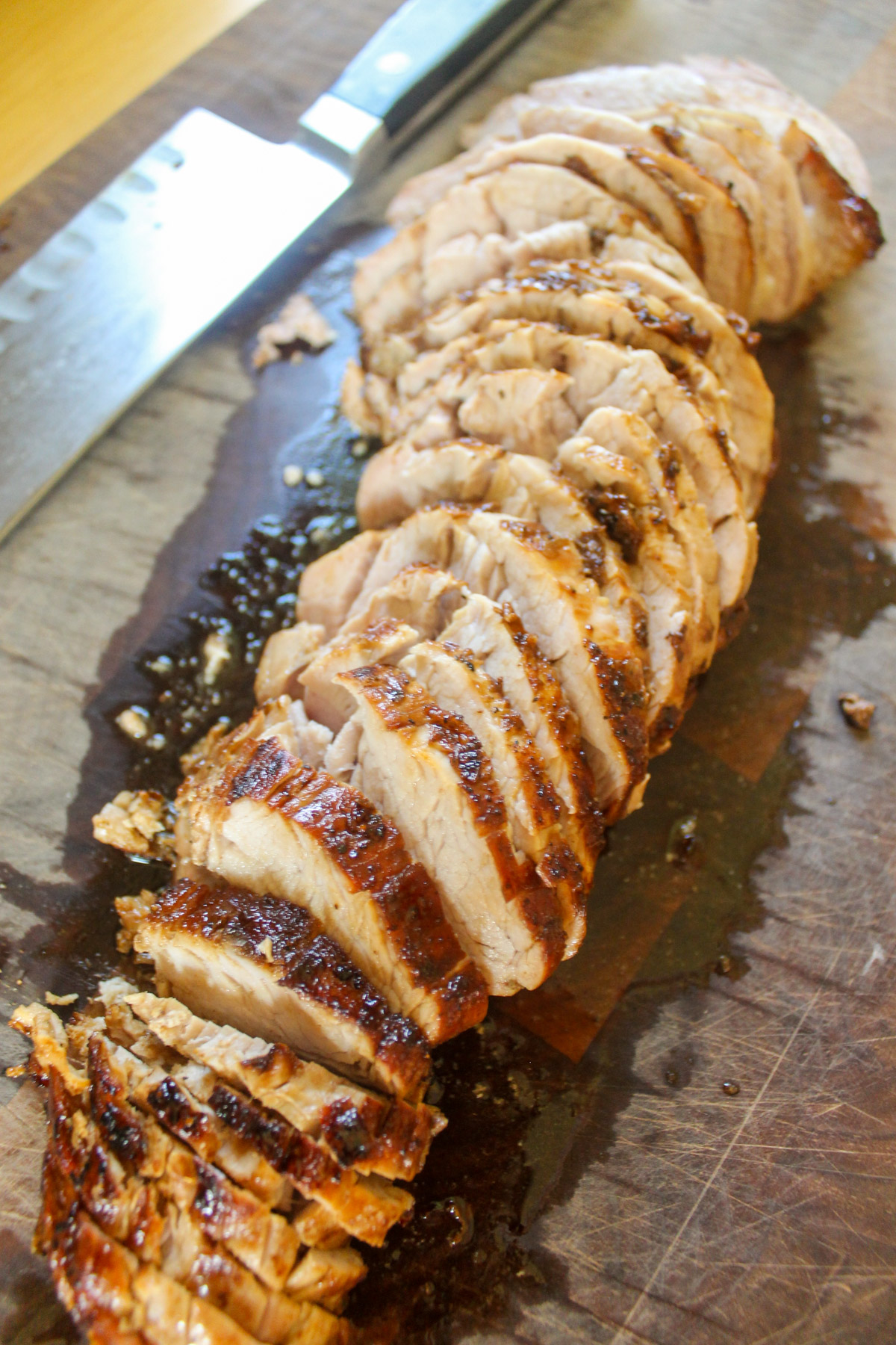 Sliced pork tenderloin on a cutting board.
