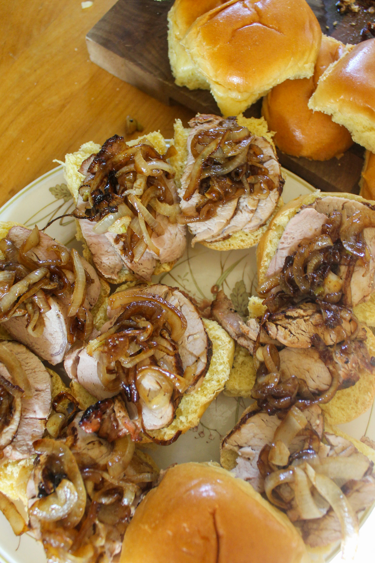 Assembling pork tenderloin sliders with caramelized onions.