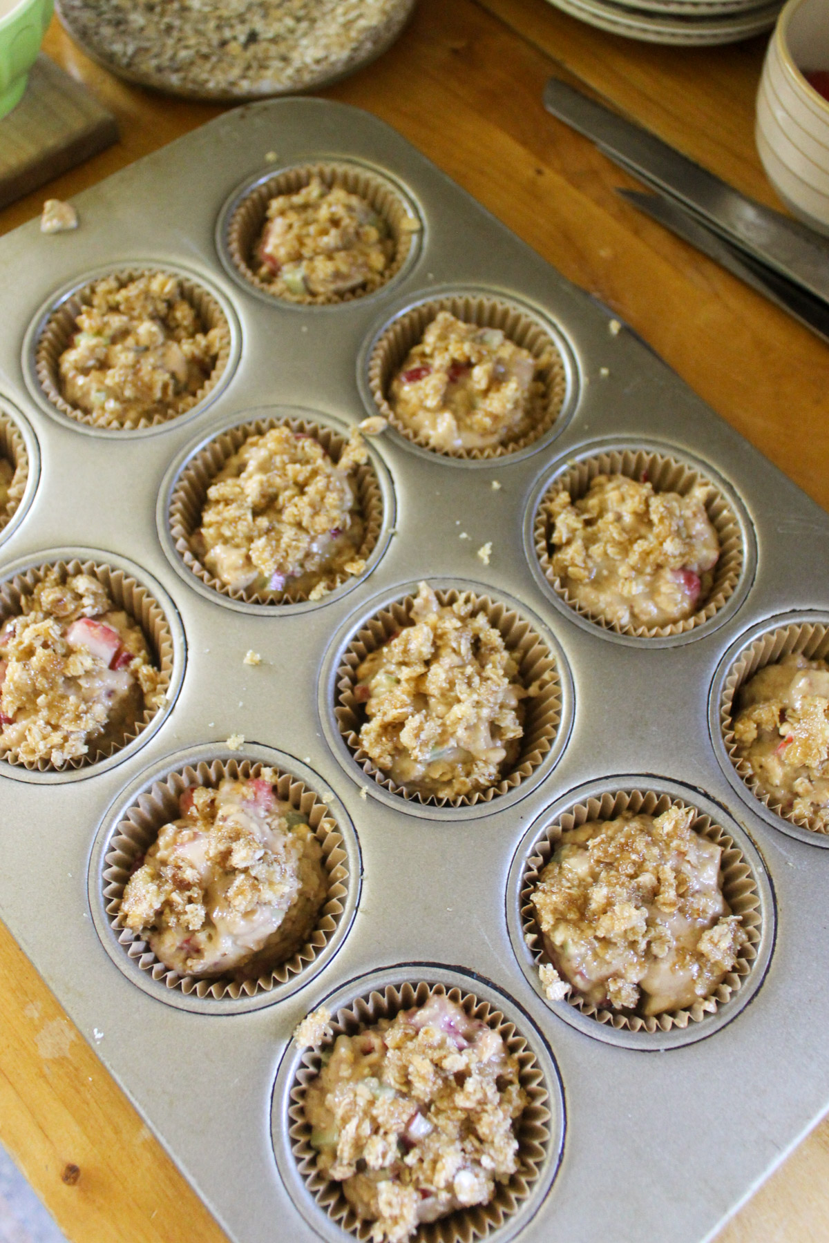 A muffin tin filled with strawberry rhubarb muffin batter.