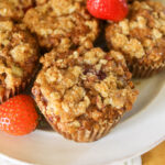 Healthier Strawberry Rhubarb Muffins on a plate with fresh strawberries.