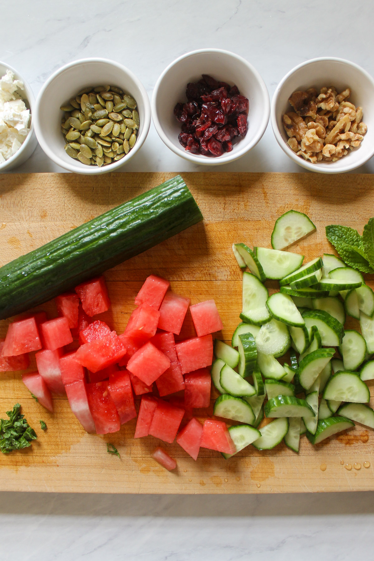Chopped cucumber and watermelon on a cutting board.