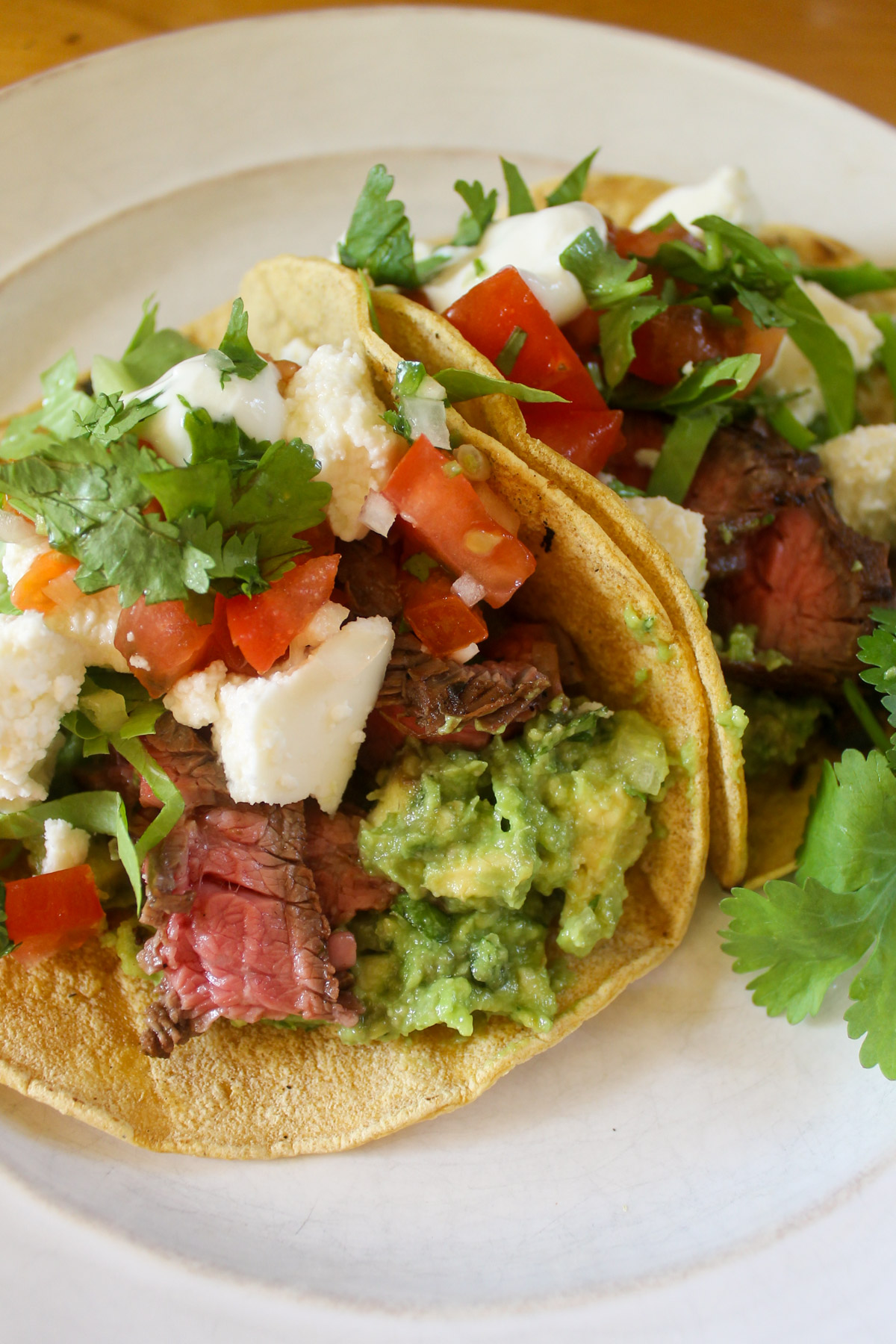 Flank steak tacos in corn tortillas with toppings.