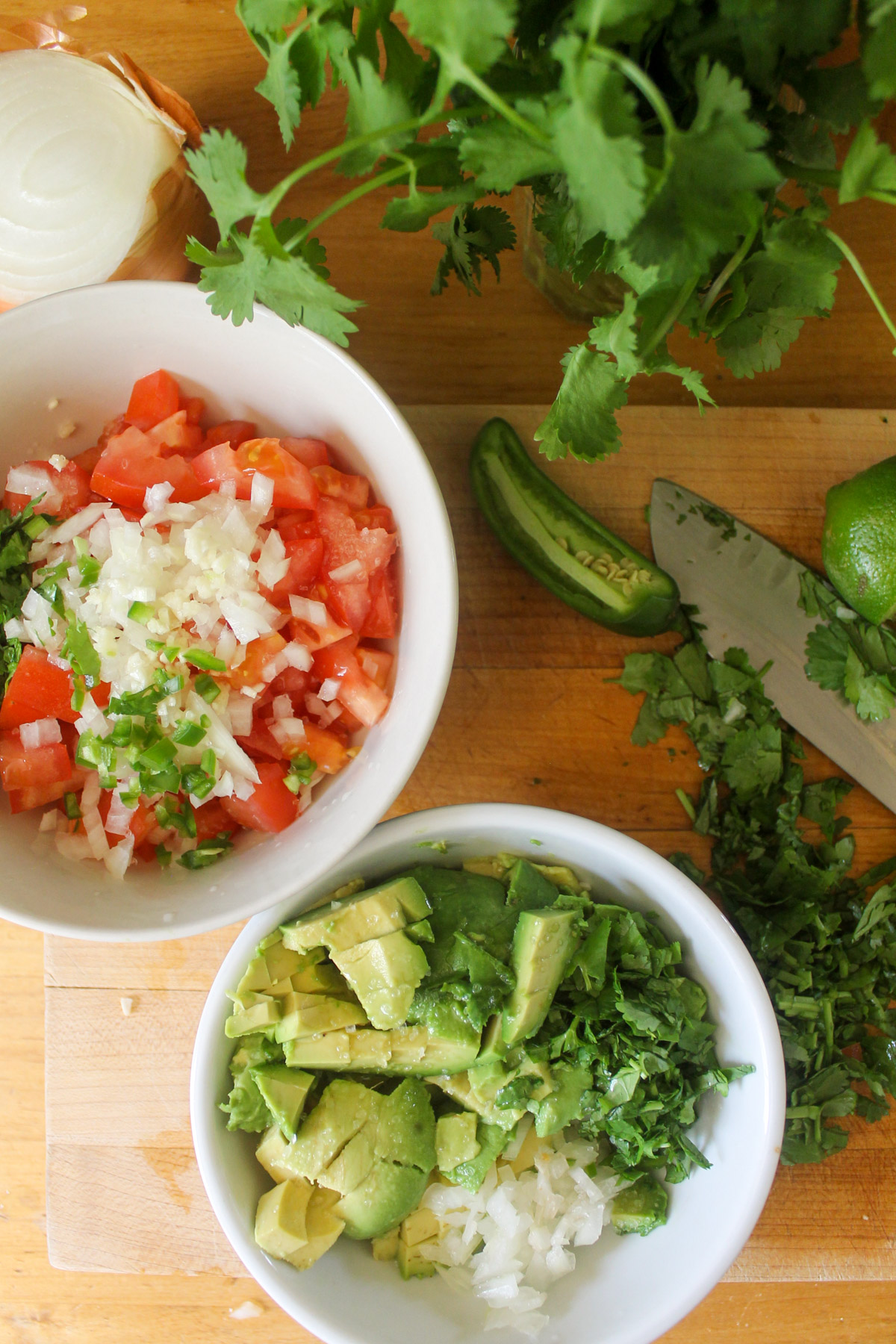 Two bowls of homemade pico de gallo salsa and guacamole.