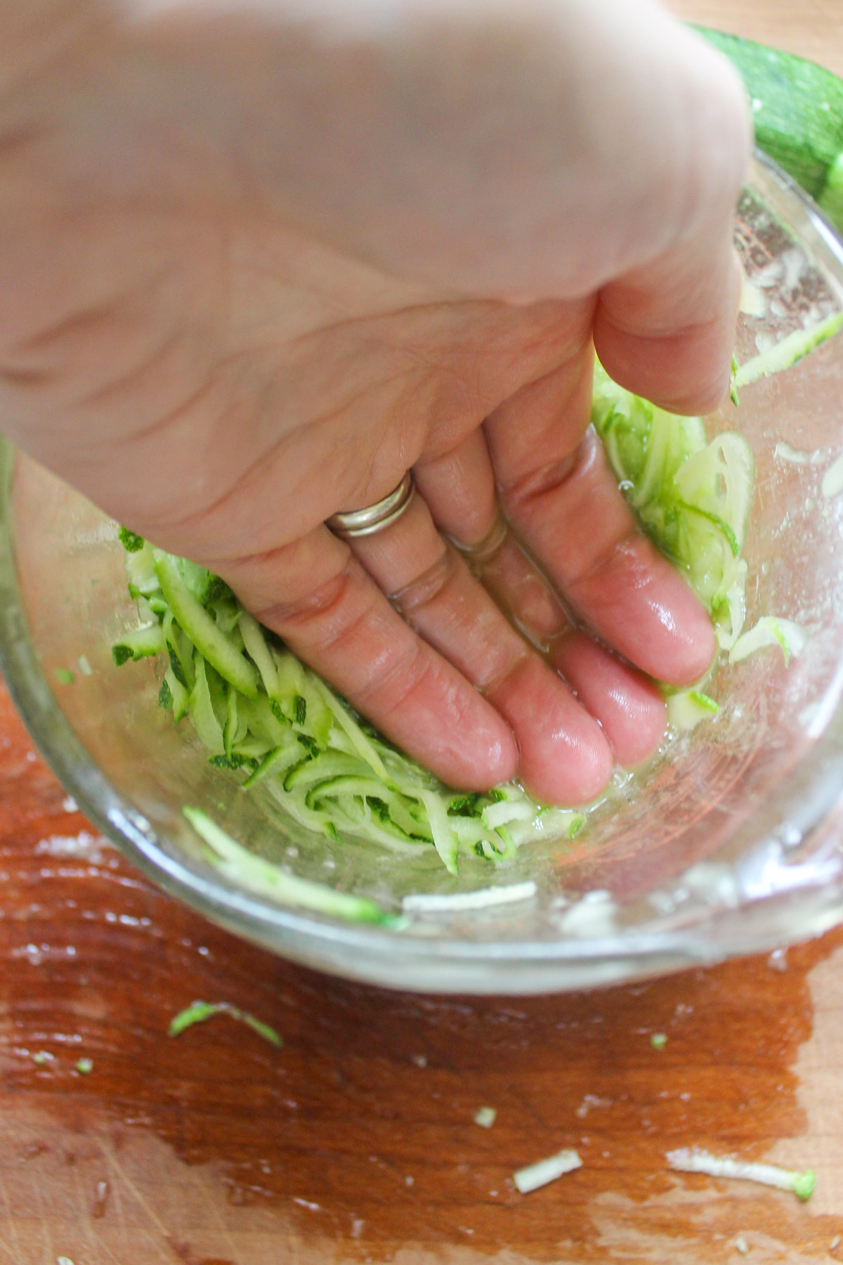 Pressing the water out of shredded zucchini in a measuring cup.