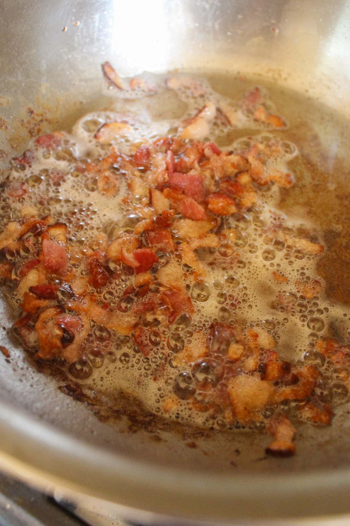 Chopped bacon frying in a skillet.