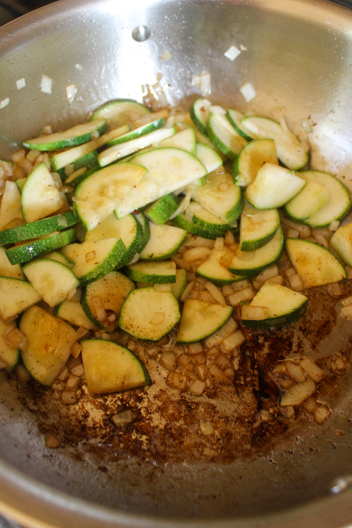 Sautéing onions and zucchini in a skillet.