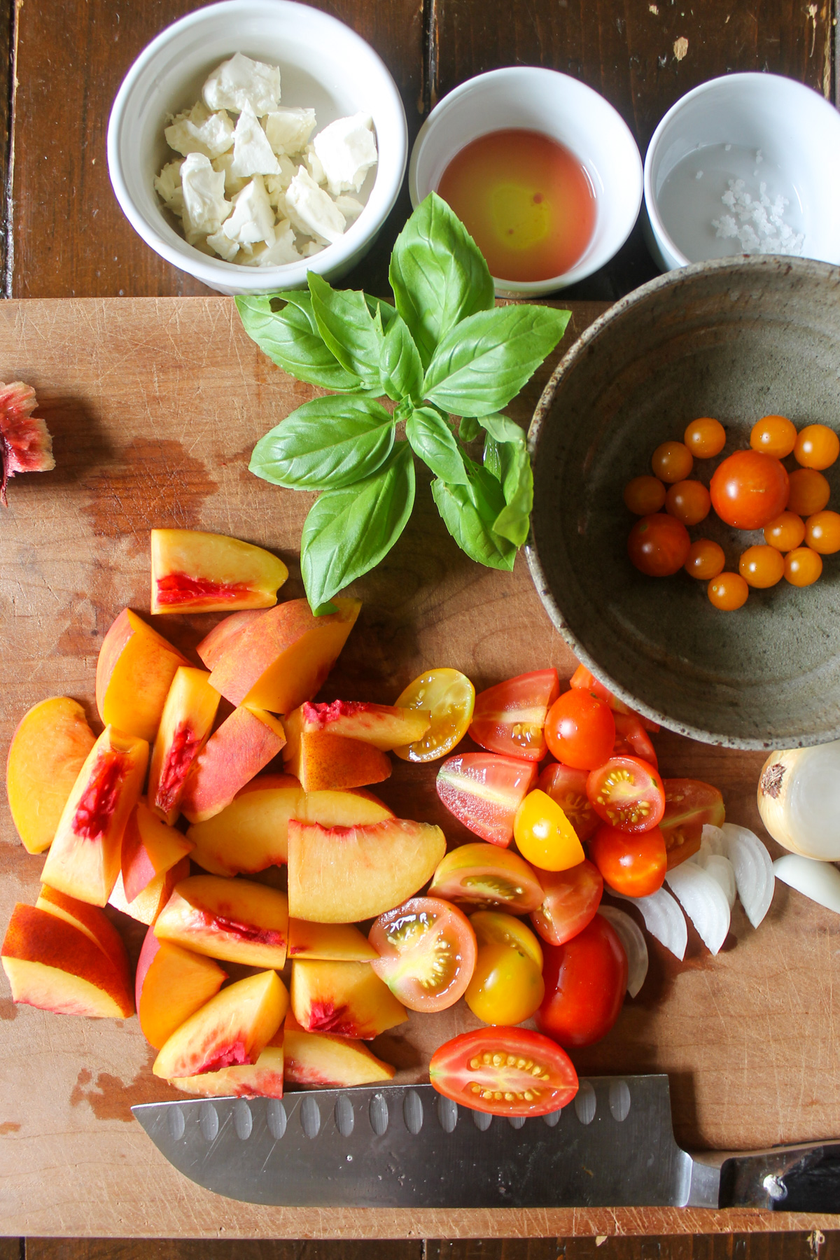 Chopping peaches and tomatoes on a cutting board.