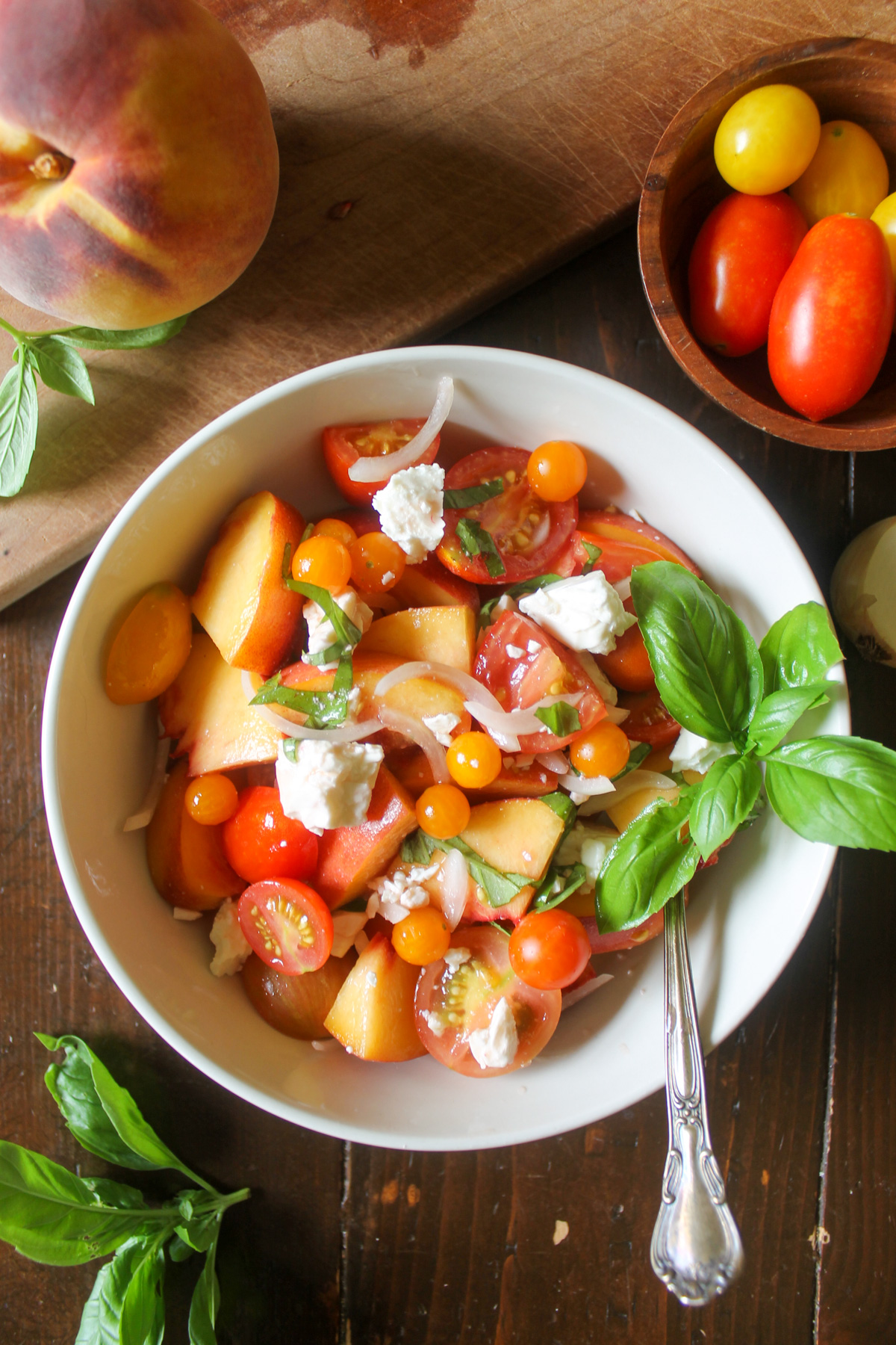 A bowl of peach tomato salad with feta and basil.