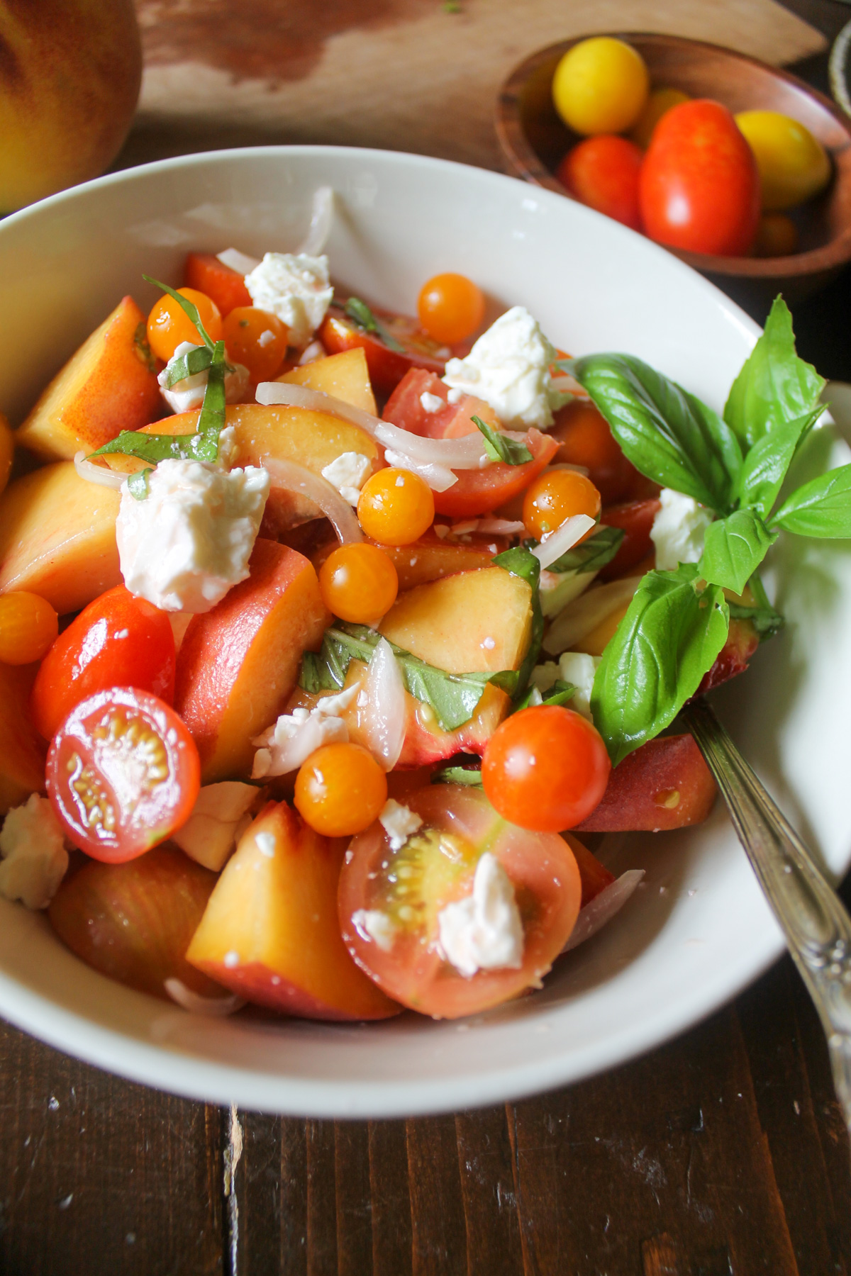 Peaches and tomatoes with feta and onion in a salad.