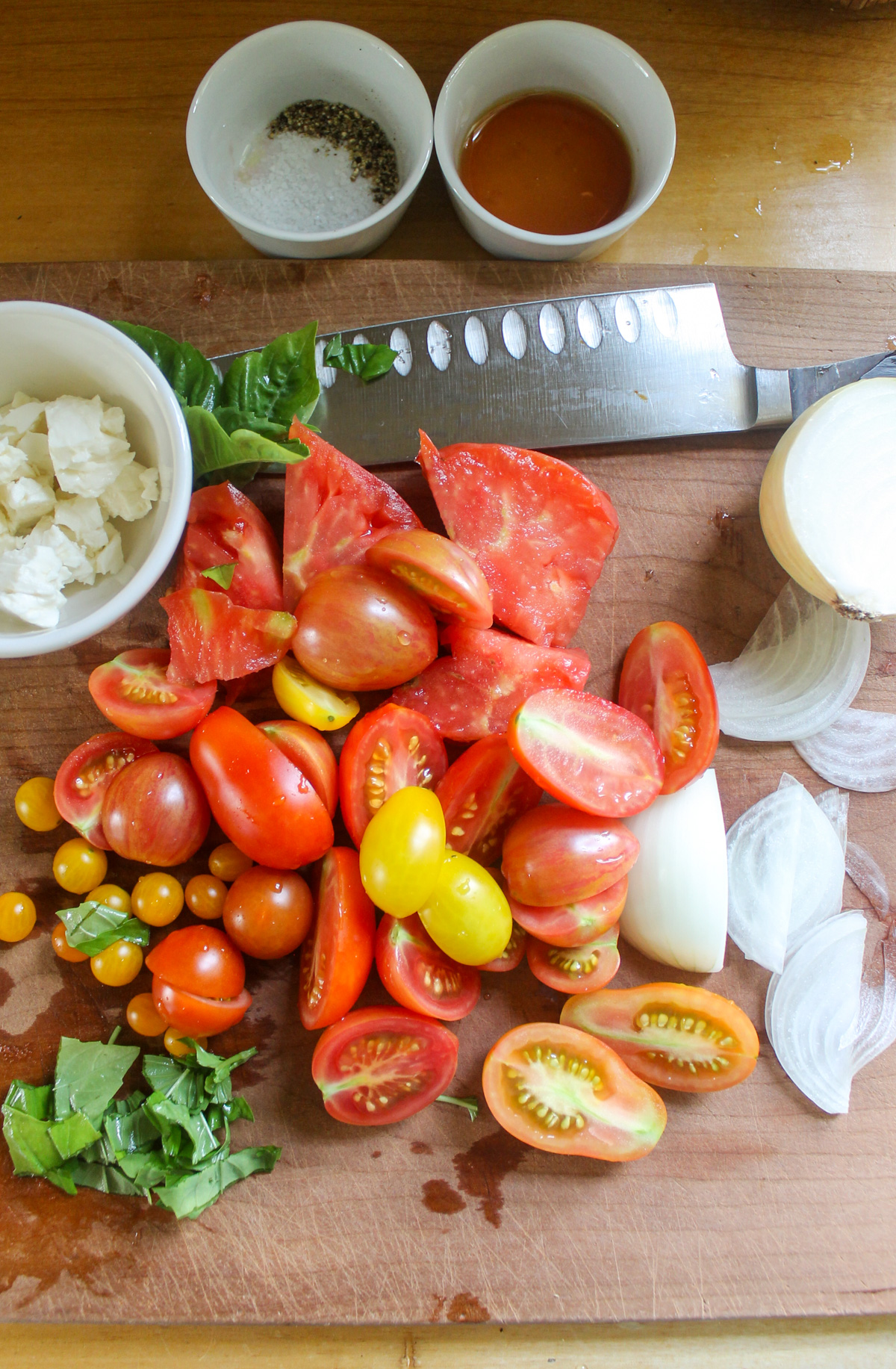 Tomatoes and onions sliced on a cutting board.