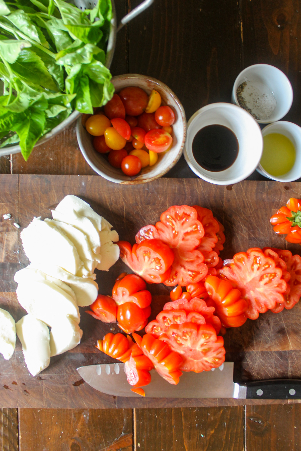 Slicing tomatoes and fresh mozzarella cheese on a cutting board.