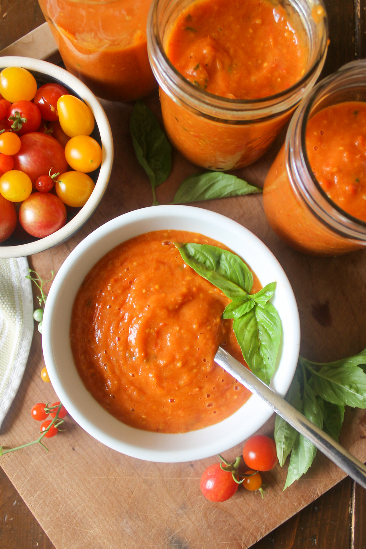 Cherry tomato sauce in jars and in a bowl.