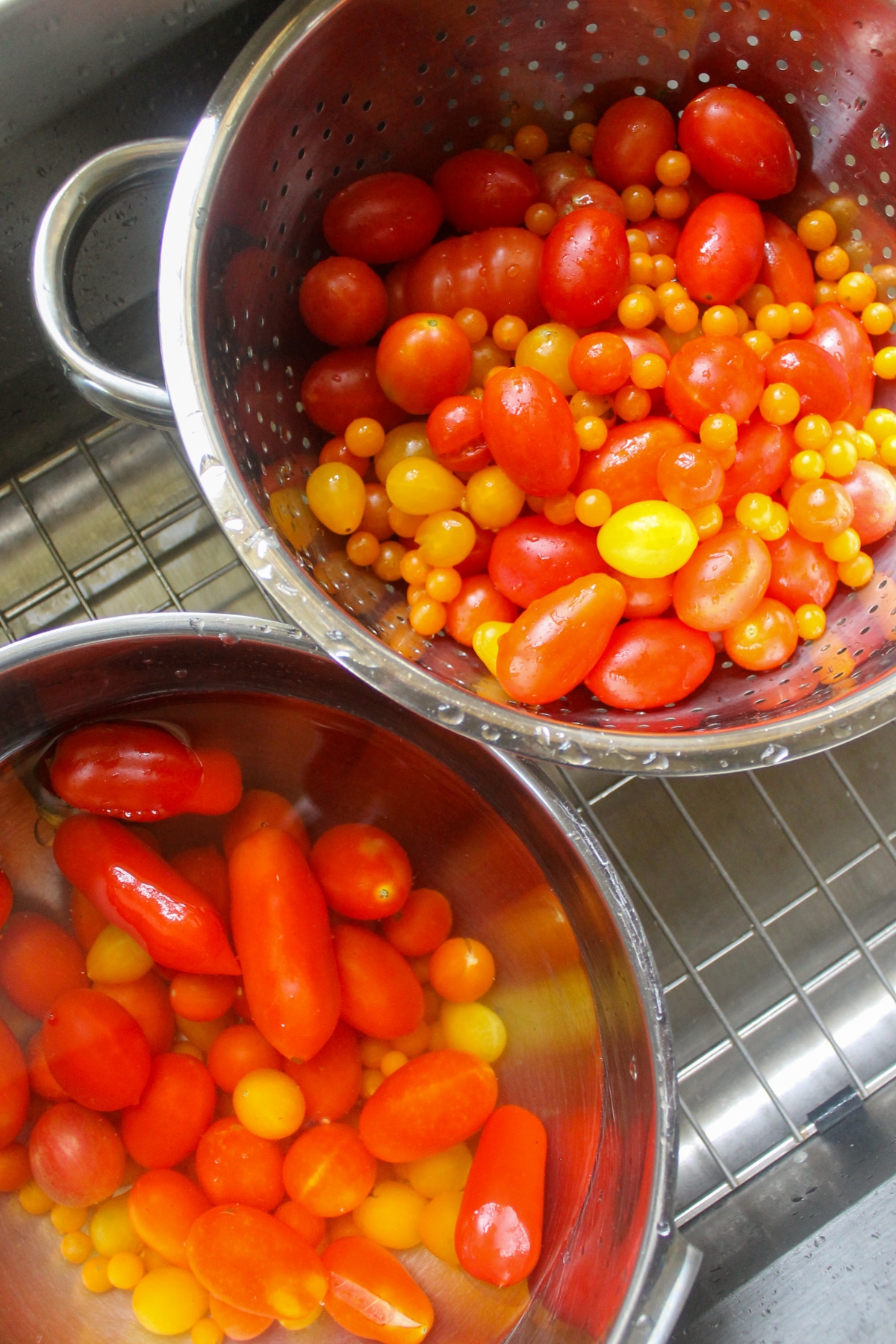 Washing tomatoes in a bowl and colander in the sink.