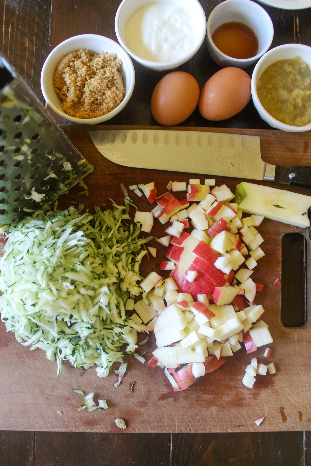 Chopped apple and shredded zucchini on a cutting board.