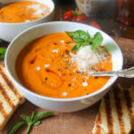White bowl of blended sweet potato and tomato soup.