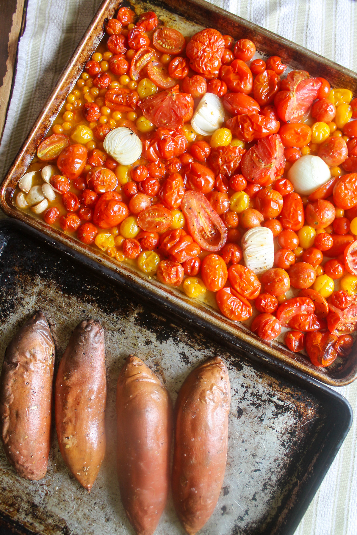 Roasted tomatoes and sweet potatoes on large sheet pans.
