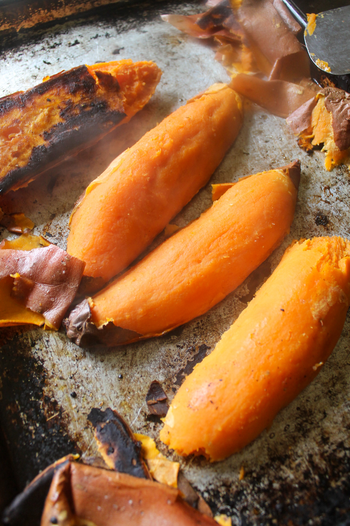 Roasted sweet potatoes on a sheet pan with peeling removed.