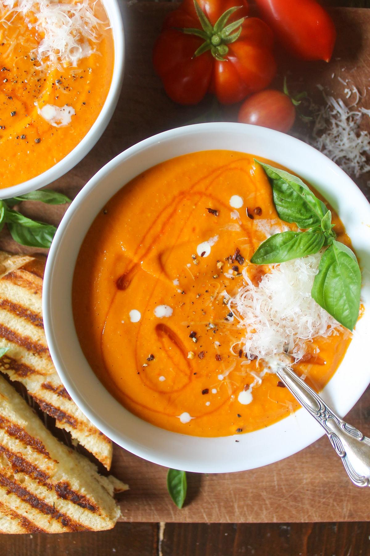 Bowls of sweet potato tomato soup drizzled with honey and basil.