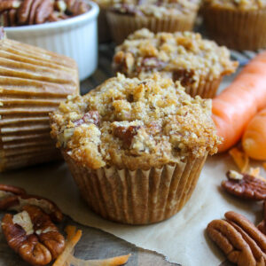 Carrot Muffins on a board with pecans and carrots.