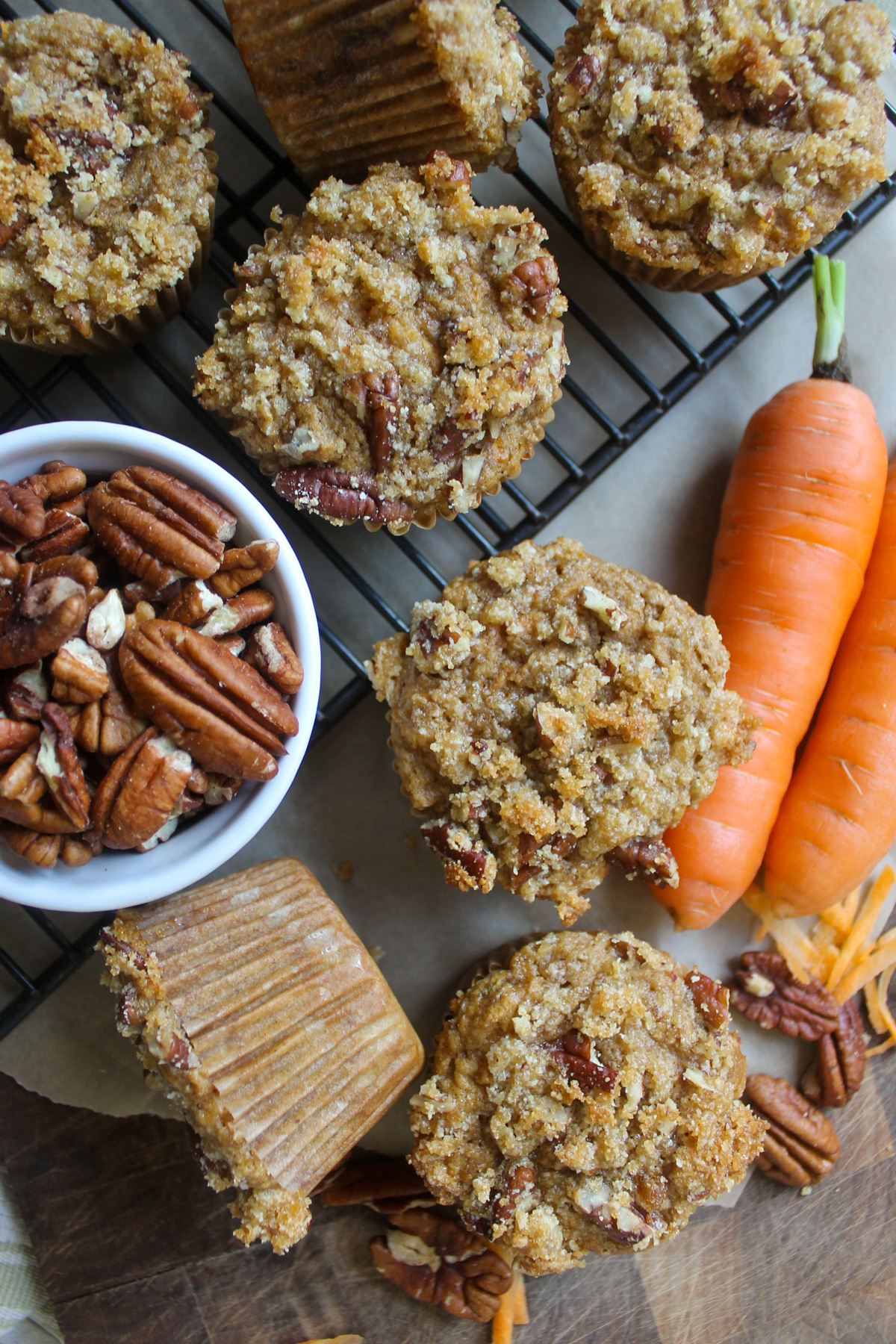 Carrot applesauce muffins on a wire rack with a bowl of pecans.